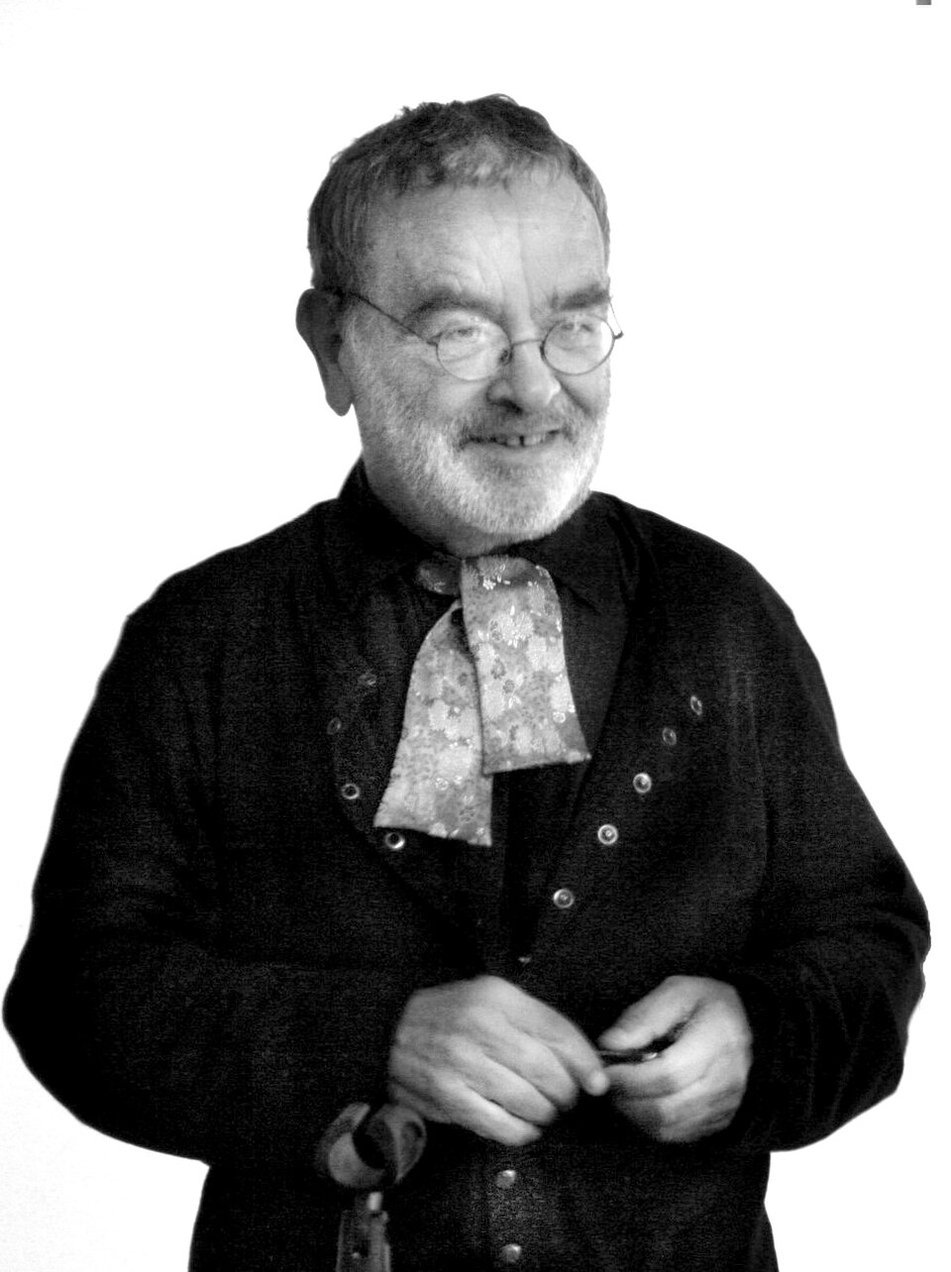 Retrato en blanco y negro de Fernando Arrabal, mayor, sonriente, con gafas redondas y barba