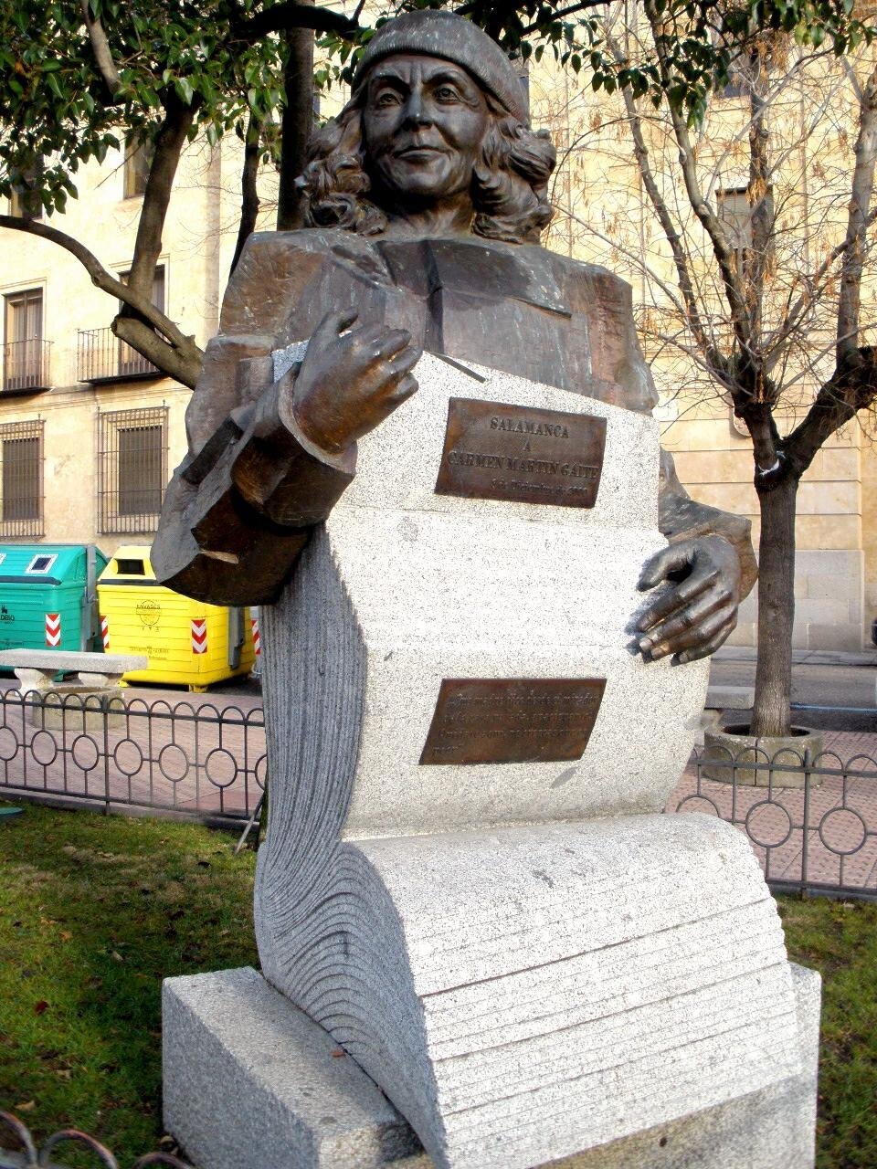 Busto de bronce de Carmen Martín Gaite, con boina y una pluma en la mano, sobre un bloque de granito con forma de hojas de papel